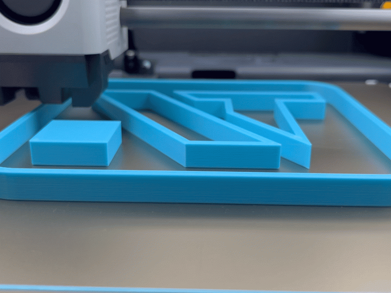 FDM-Druck 3D-Drucker erstellt im FDM-Druckverfahren das Navkotec-Logo. Eine Andeutung von N und T mit einem Viereck in der linken Ecke.
