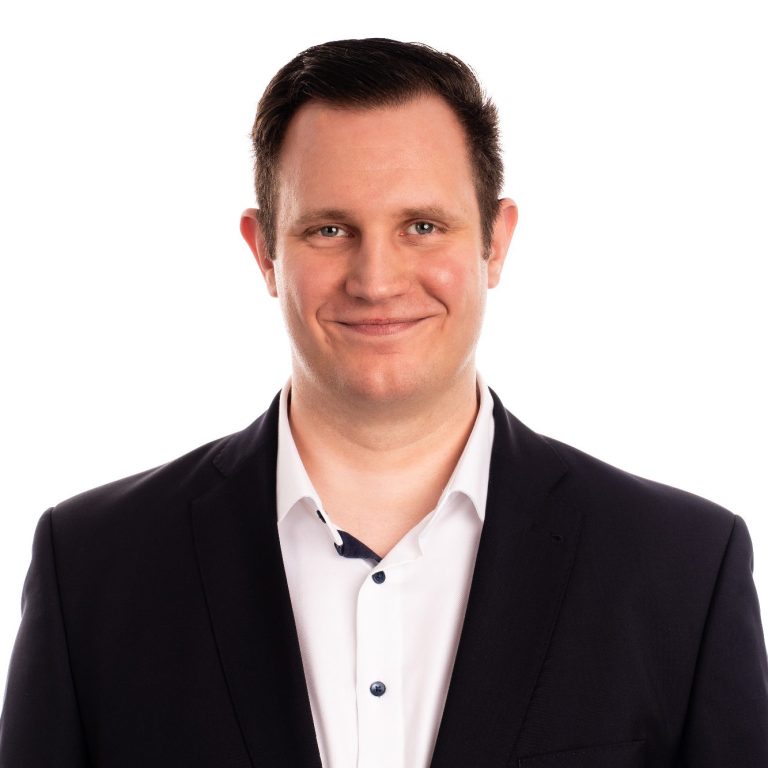 Silvan Kowalzik in Anzug mit lächelndem Gesicht, hellem Hemd und dunkler Jacke.